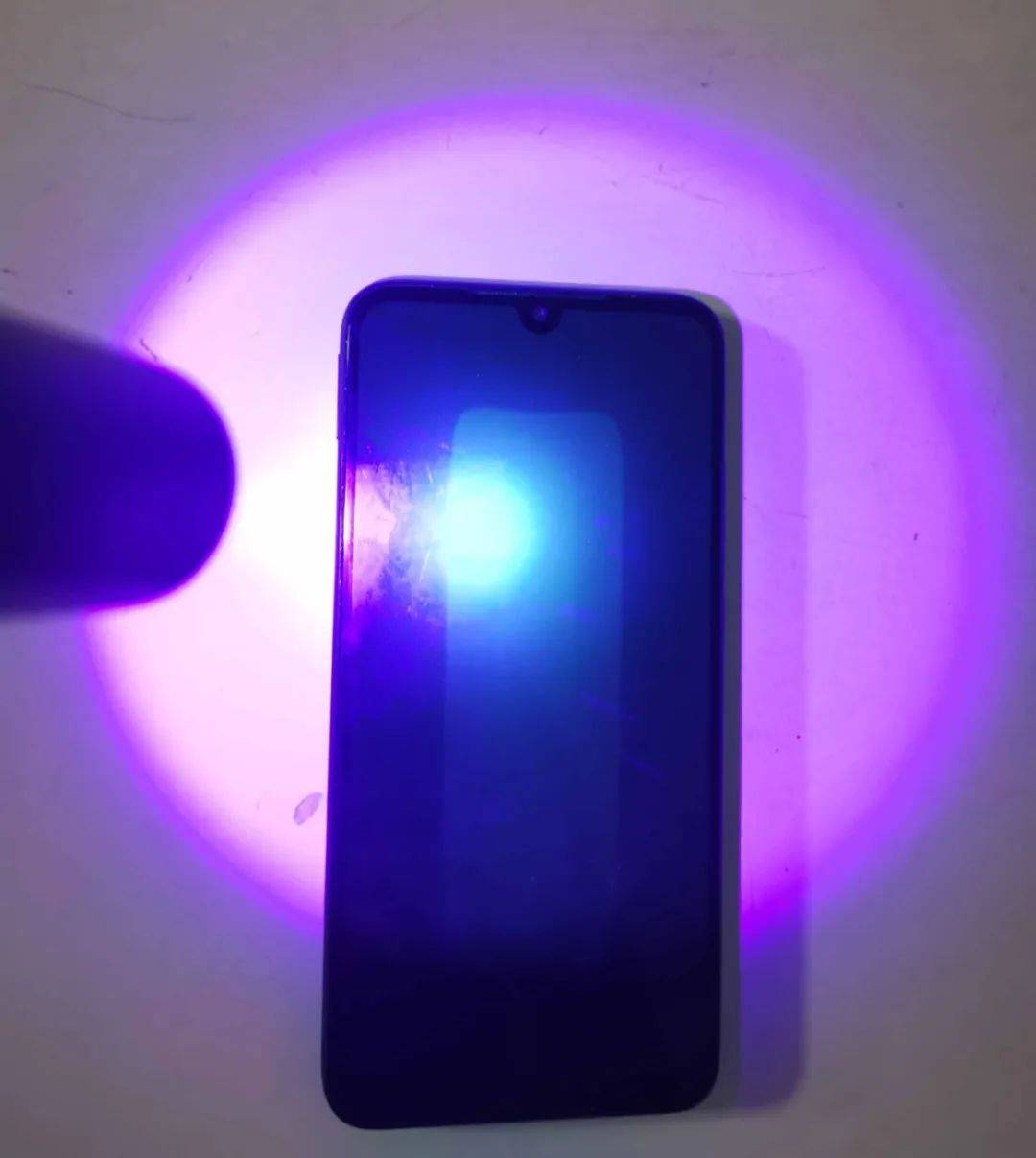 意外用紫光手电筒照射手机屏幕出现不明物