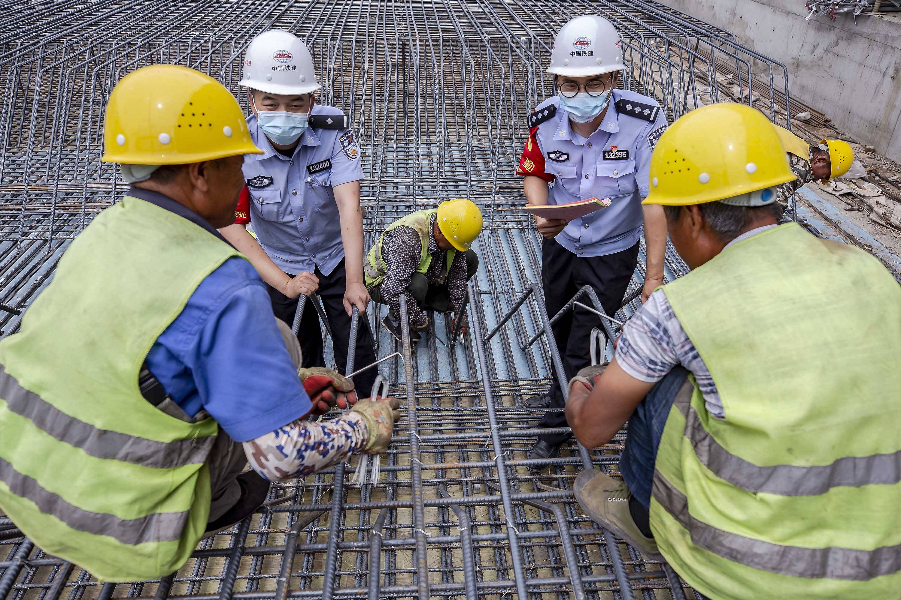 民警在铁路桥涵施工现场向施工人员讲解安全生产注意事项.