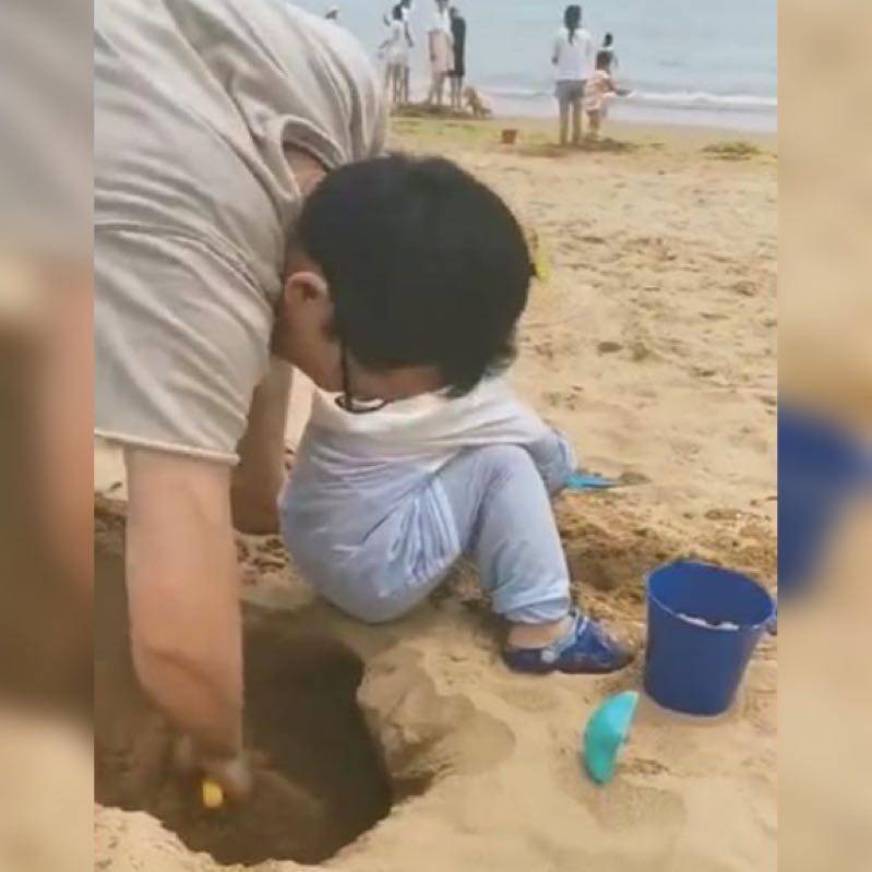 原创亲爸带娃在沙滩上给娃“挖坑”火了，网友：安全的时候老爸最危险