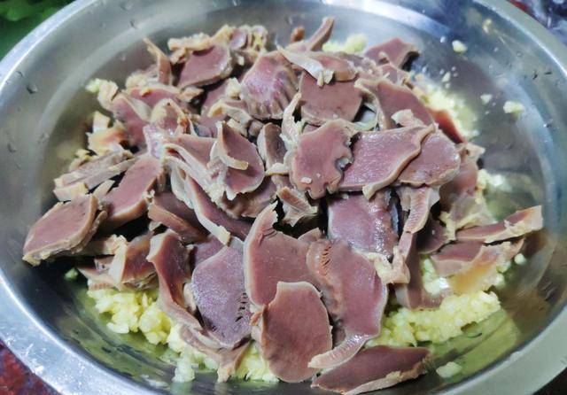 8,浸泡好的鸭胗捞出,放到案板上,用切熟肉的刀将鸭胗切成片,尽量切得