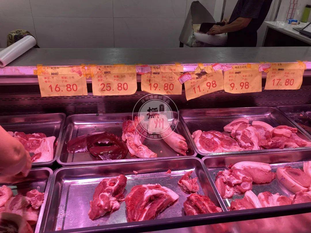 肉摊经营户王大姐和她老公正忙着给顾客称肉"这段时间猪肉确实降了些