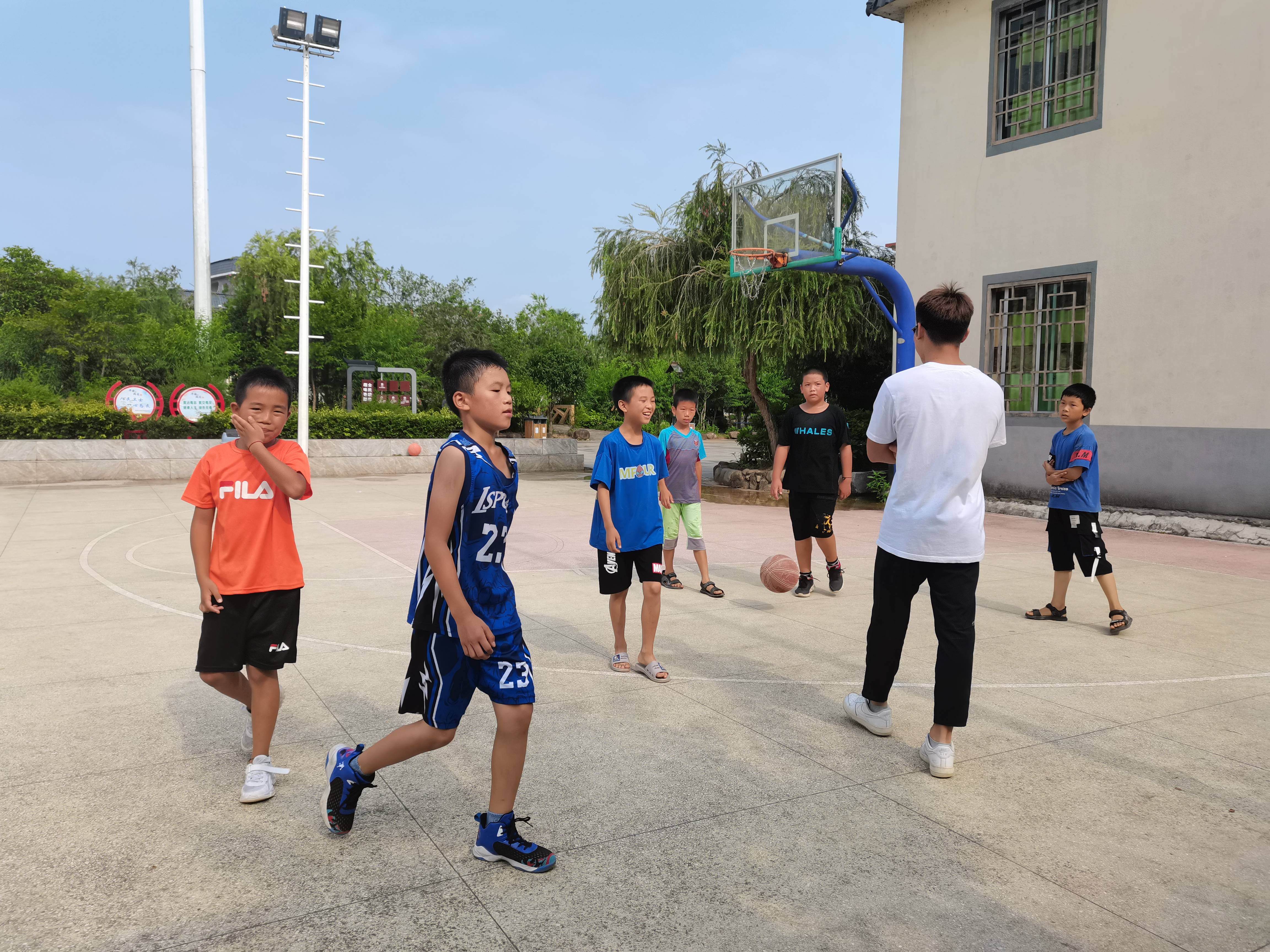 7月17日"心之源"社会实践队的队员继续带领着同学们在篮球场上训练