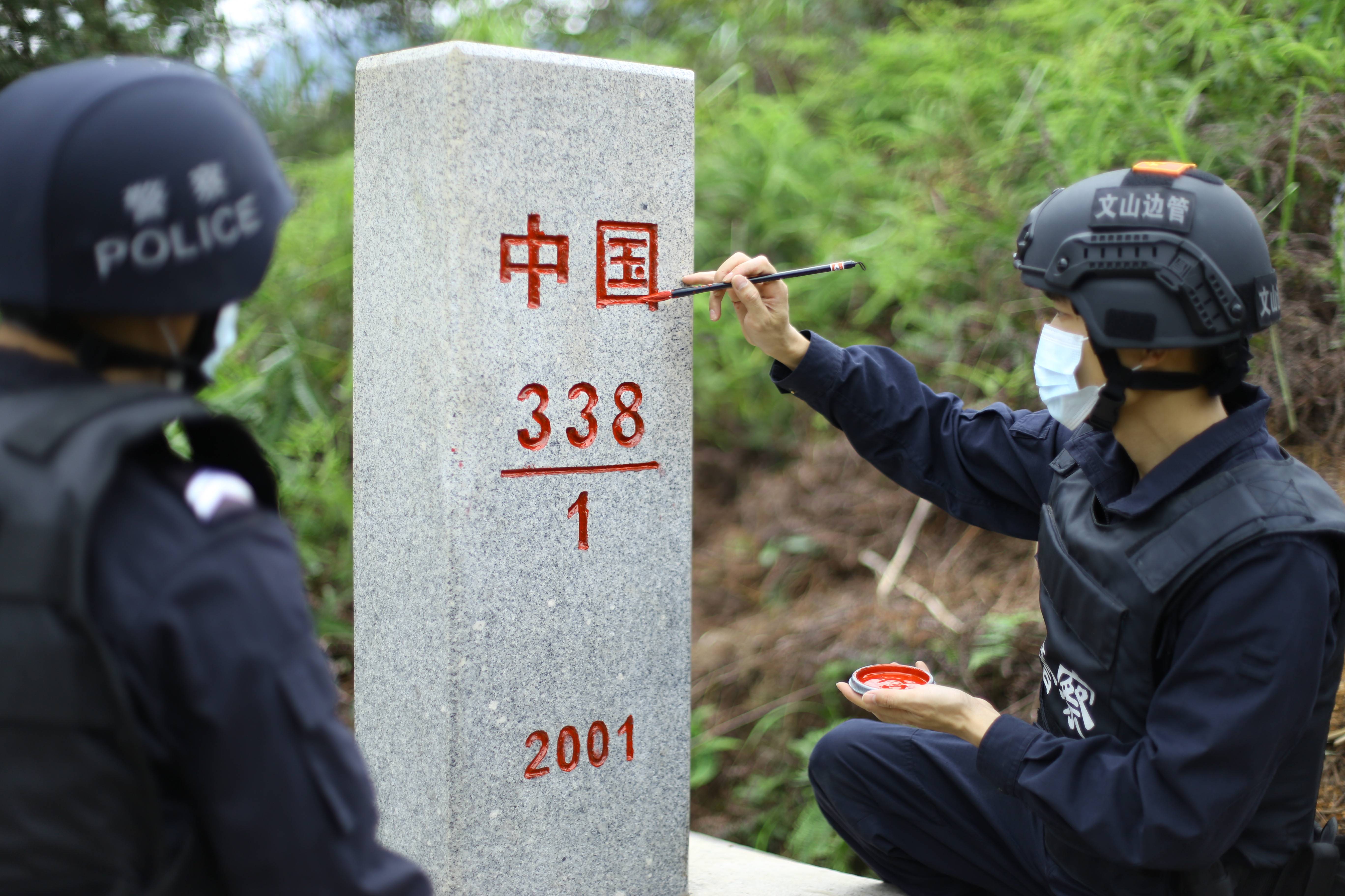 图为云南文山边境管理支队八布边境派出所民警对界碑上的"中国"字样和