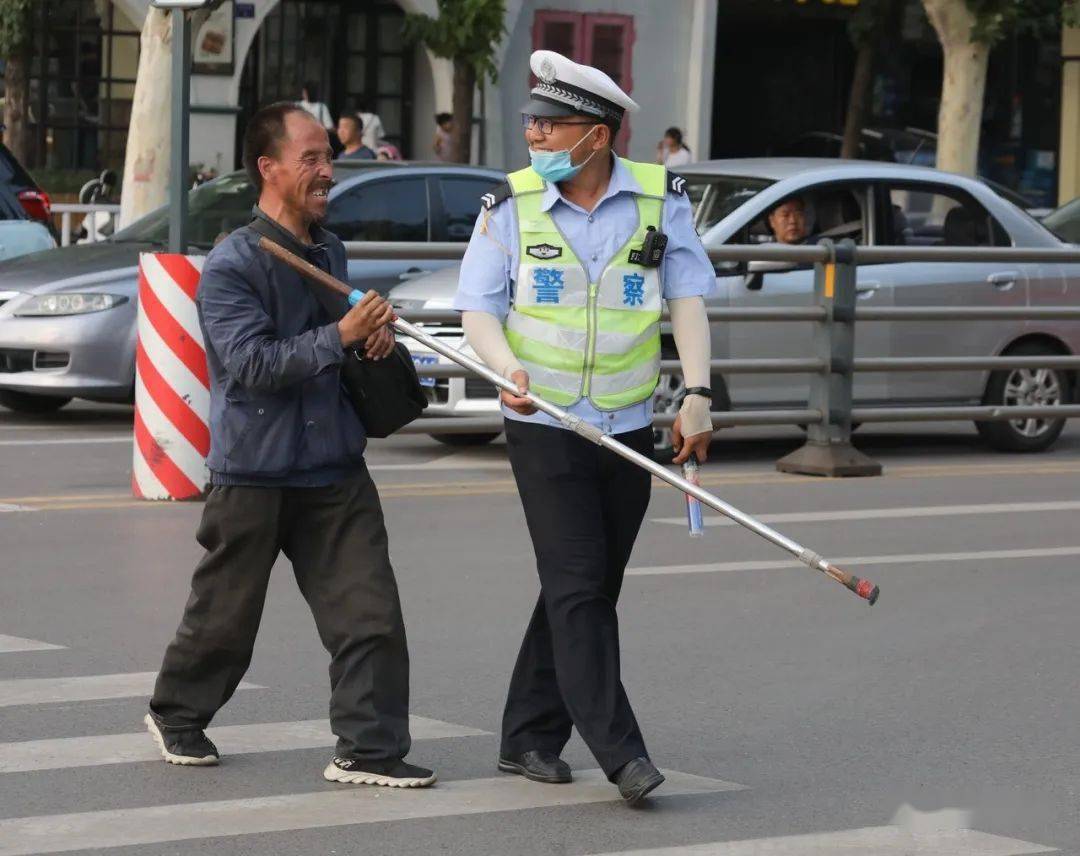 帮助盲人过马路参与劝导的志愿者劝导戴头盔行人闯红灯被查并进行处罚