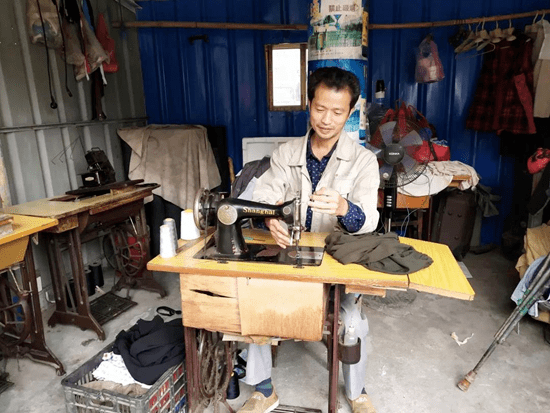 傅水根在裁缝店里给客人缝衣服