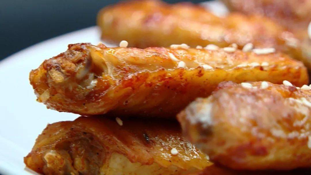 在辣味鸡翅和蜜汁鸡翅上撒些许白芝麻,各种风味的烤鸡翅可以摆盘上桌