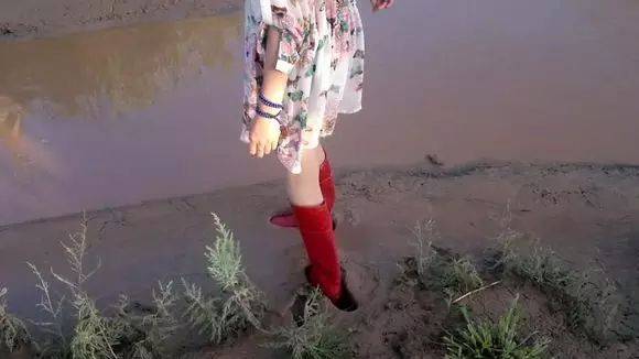 美女穿红色雨靴泥河里摸鱼拔不出腿