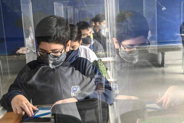 哥伦比亚学校重新开学 学生戴口罩在挡板里学习