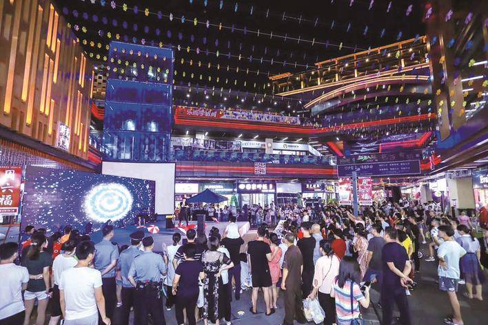 图为吾悦夜市内人流如织,市民在中心广场欣赏精彩的魔术表演. 盛磊 摄