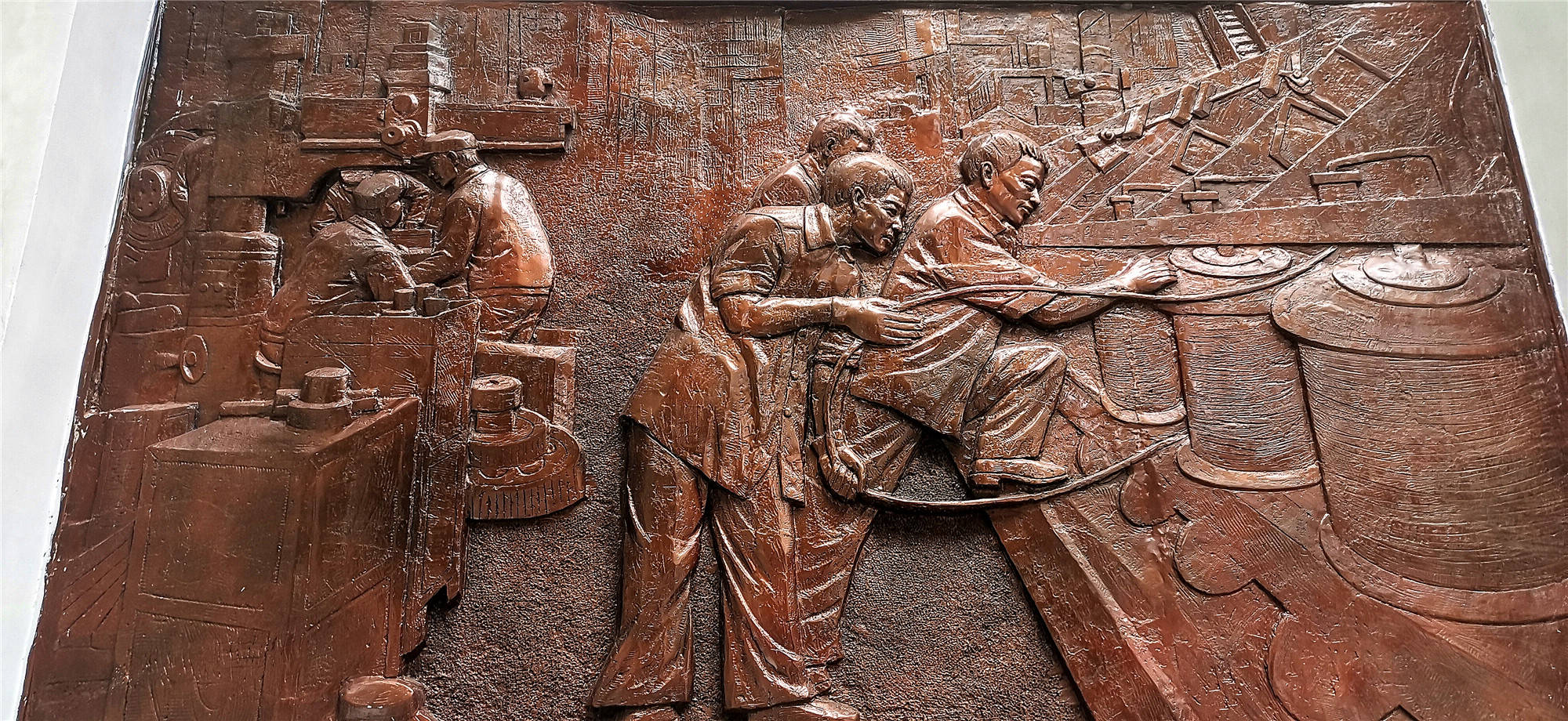 一台台老工业企业生产机械设备陈列在道路一侧,一幅幅古铜色工业浮雕