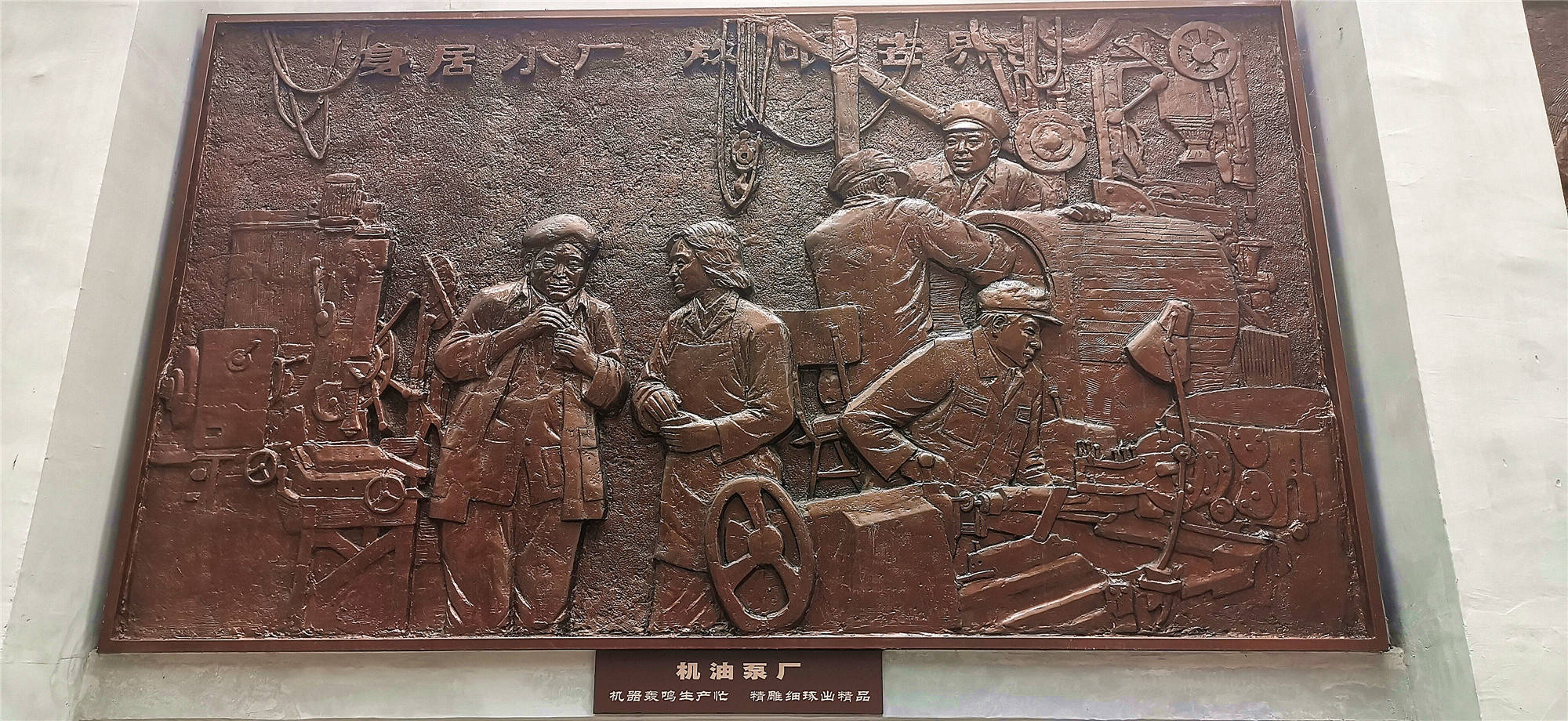 一台台老工业企业生产机械设备陈列在道路一侧,一幅幅古铜色工业浮雕