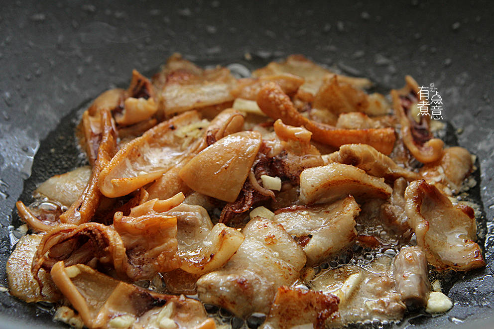 5,煎到鱿鱼干卷曲,表面起皱时就差不多了,放入剁碎的姜和蒜翻炒一下增