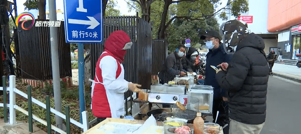 和金牛街交叉口,三位卖早点的摊贩正在寒风中为顾客准备热腾腾的早餐