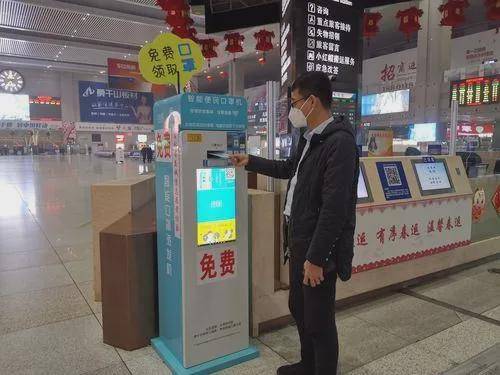 在长春站进站口,一名旅客正在智能便民口罩机前排队领取口罩.