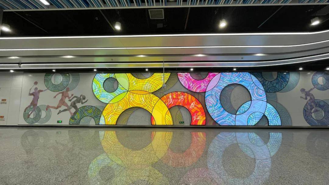 奥体中心站的文化墙以《五环同心》为主题,采用代表奥运精神的五环