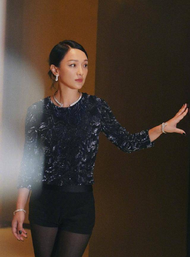 本人周迅纯黑亮片衫神情严肃，一展优雅成熟气质，上挑眼线更添娇媚