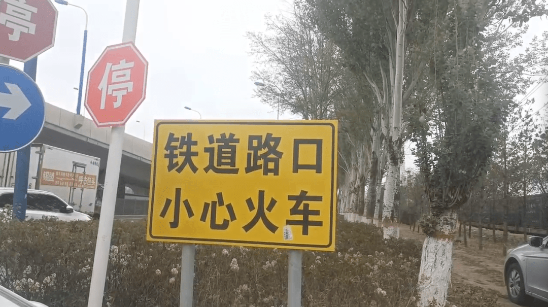 除了停车的标志,还有一面警示牌,上面写着:铁道路口,小心火车