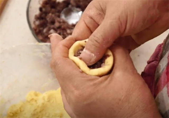 现在我们揪一小坨面搓成圆球,按出一个小窝来,包点红豆馅进去,用虎口