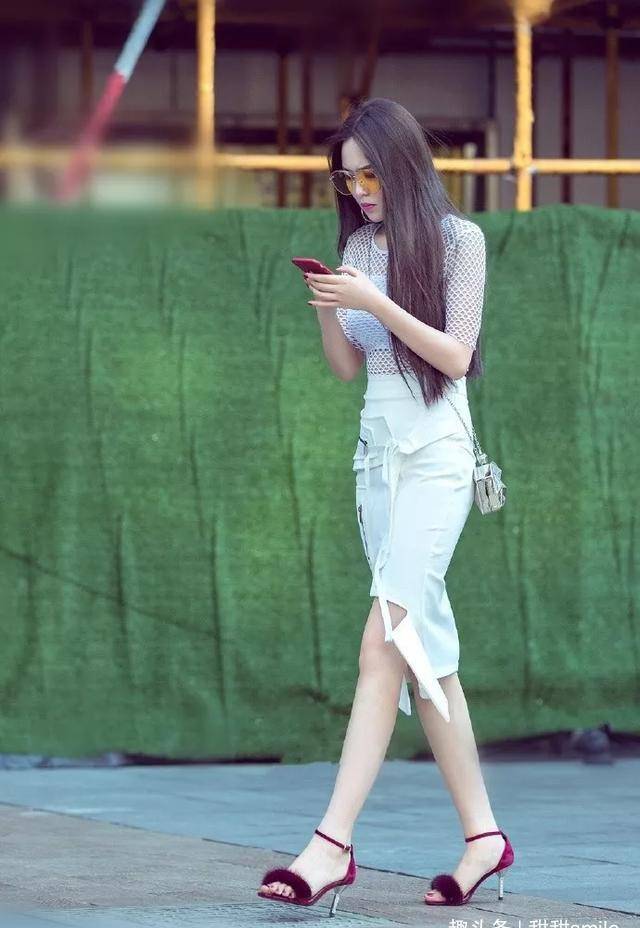 美女踩着一双酒红色的高跟凉鞋,带有绒毛的设计看上去温柔又时尚_带着