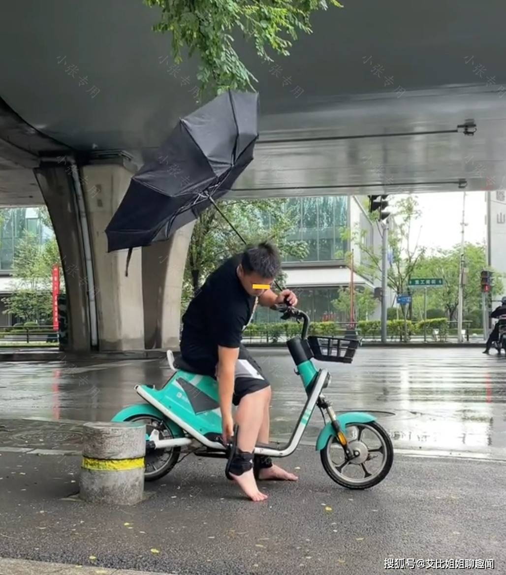 男子的拖鞋卡在脚脖子上雨伞也被吹翻场面狼狈不堪