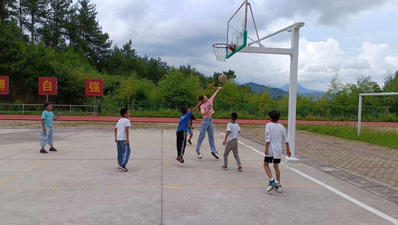 图为志愿者与学生在体育课上打篮球.