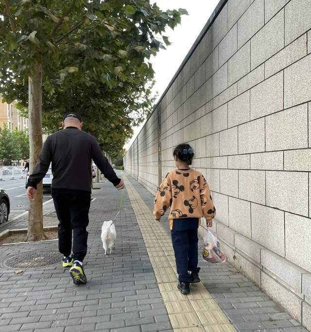 岳云鹏与小女儿遛狗散步,戴帽遮光头造型,妻子在身后拍照太温馨_郑敏