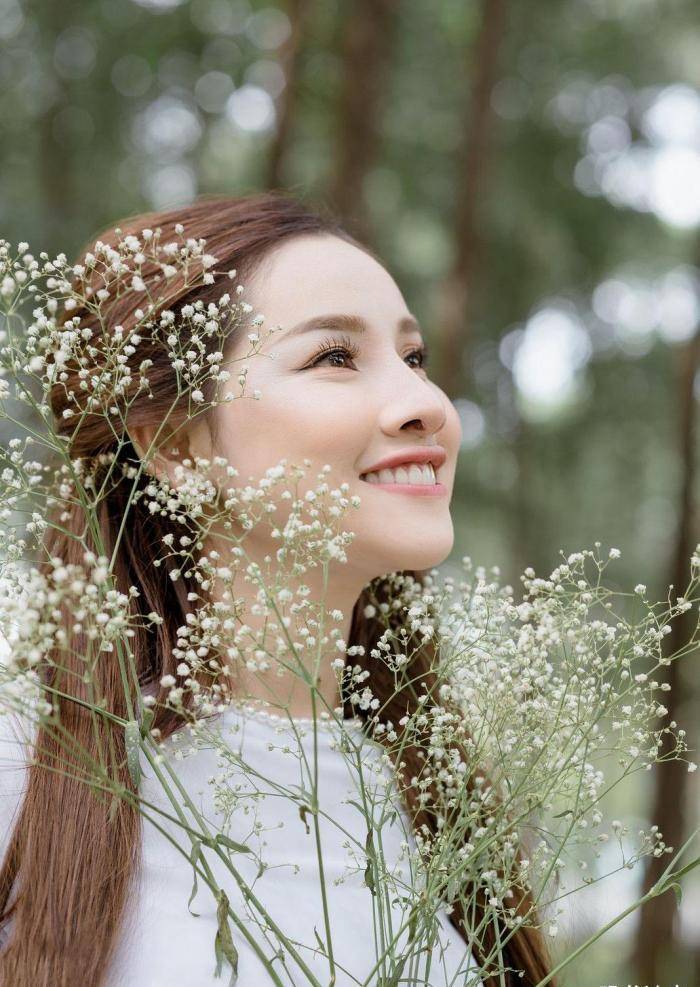 手捧鲜花,身穿白色奥黛,气质温婉,笑容阳光的国外姑娘真美