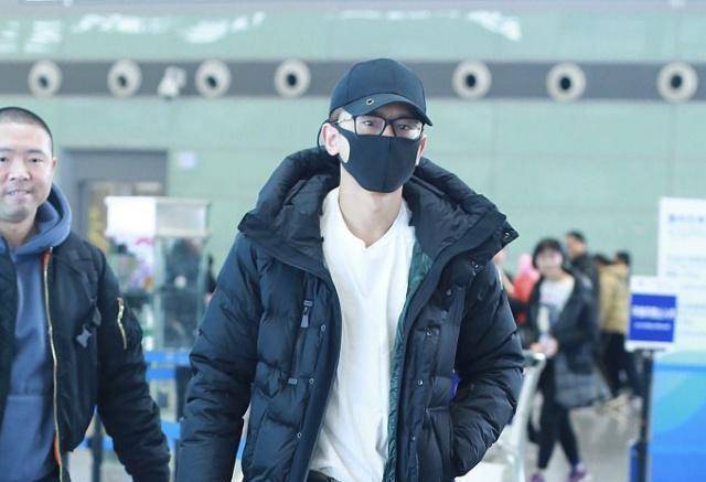 张杰穿着黑色短款棉衣,内搭纯色的白t恤,一只手插在棉衣口袋里,下面