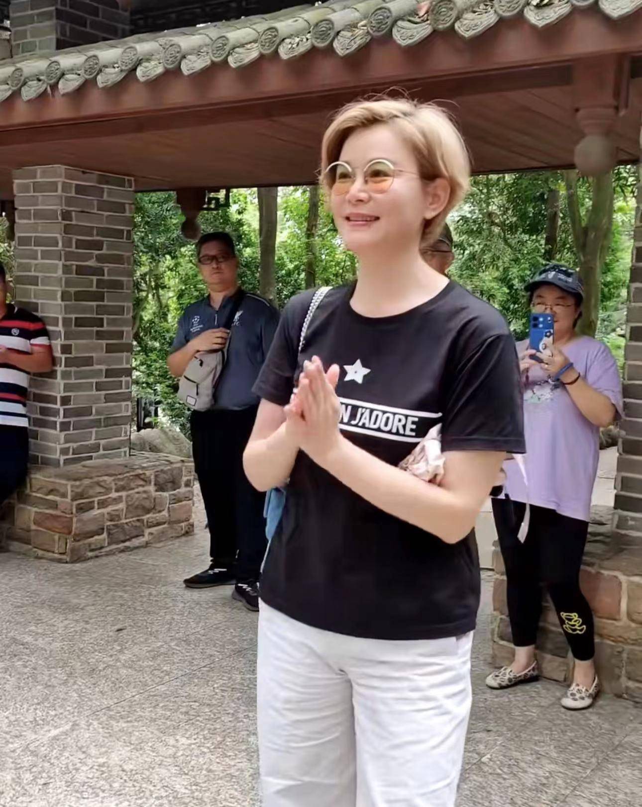 视频中,骆达华的老婆卢燕染了一头金色的短发,穿着黑色t恤,下搭白色