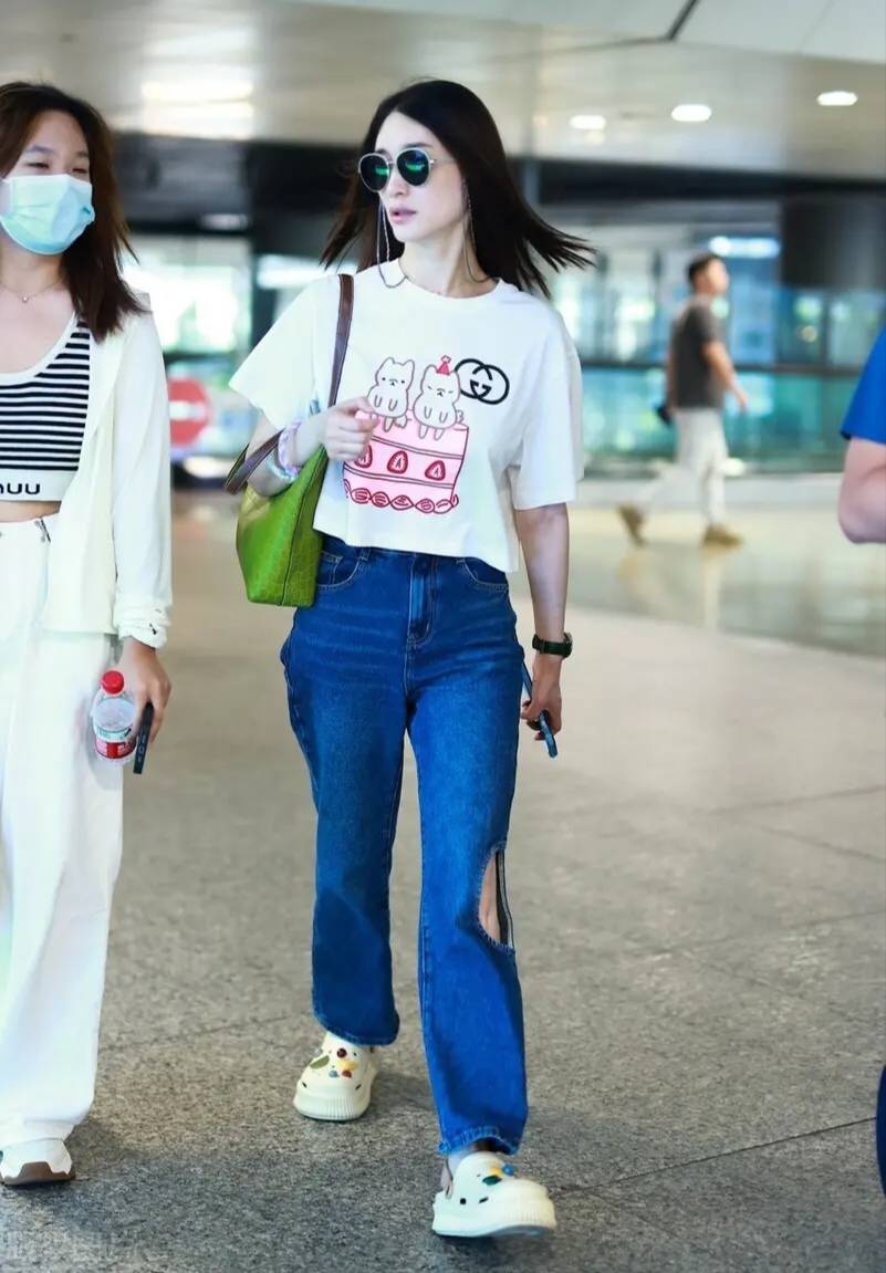 李小冉机场造型很清新,白色卡通t恤衫搭配蓝色牛仔裤,时髦减龄