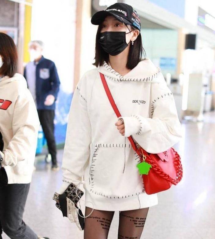 吴宣仪上半身穿着白色纸质上衣.这款纸上衣搭配黑色字母袜子.