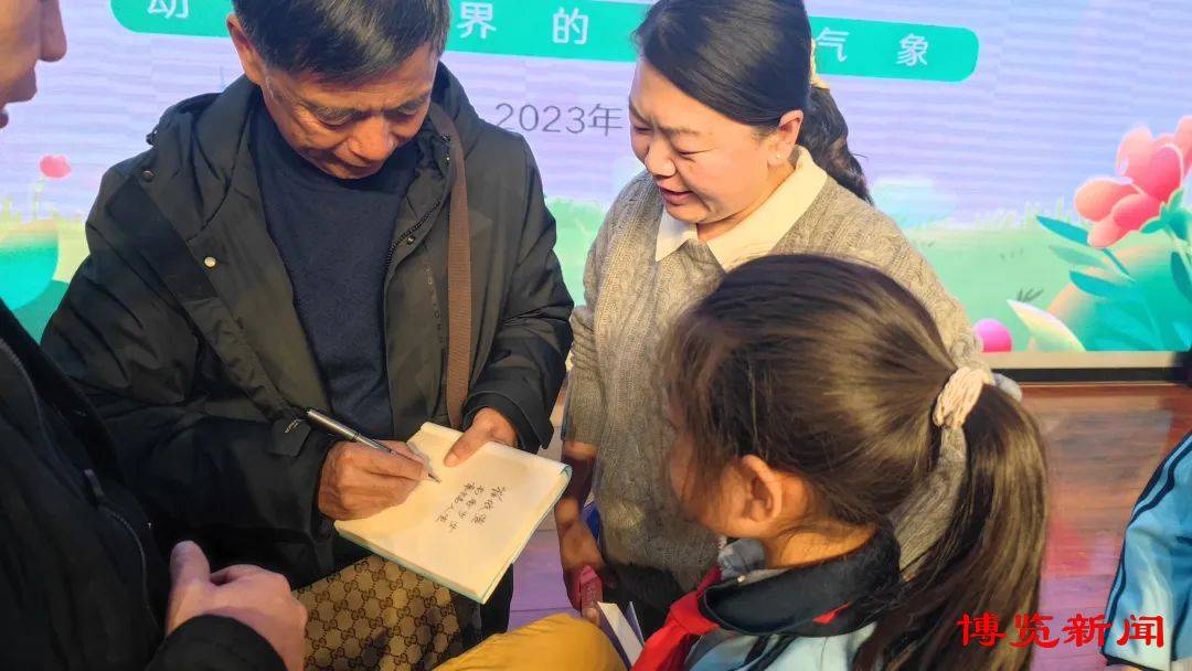 讲座结束后,沈石溪为孩子们带的书签名,并与部分师生合影留念.