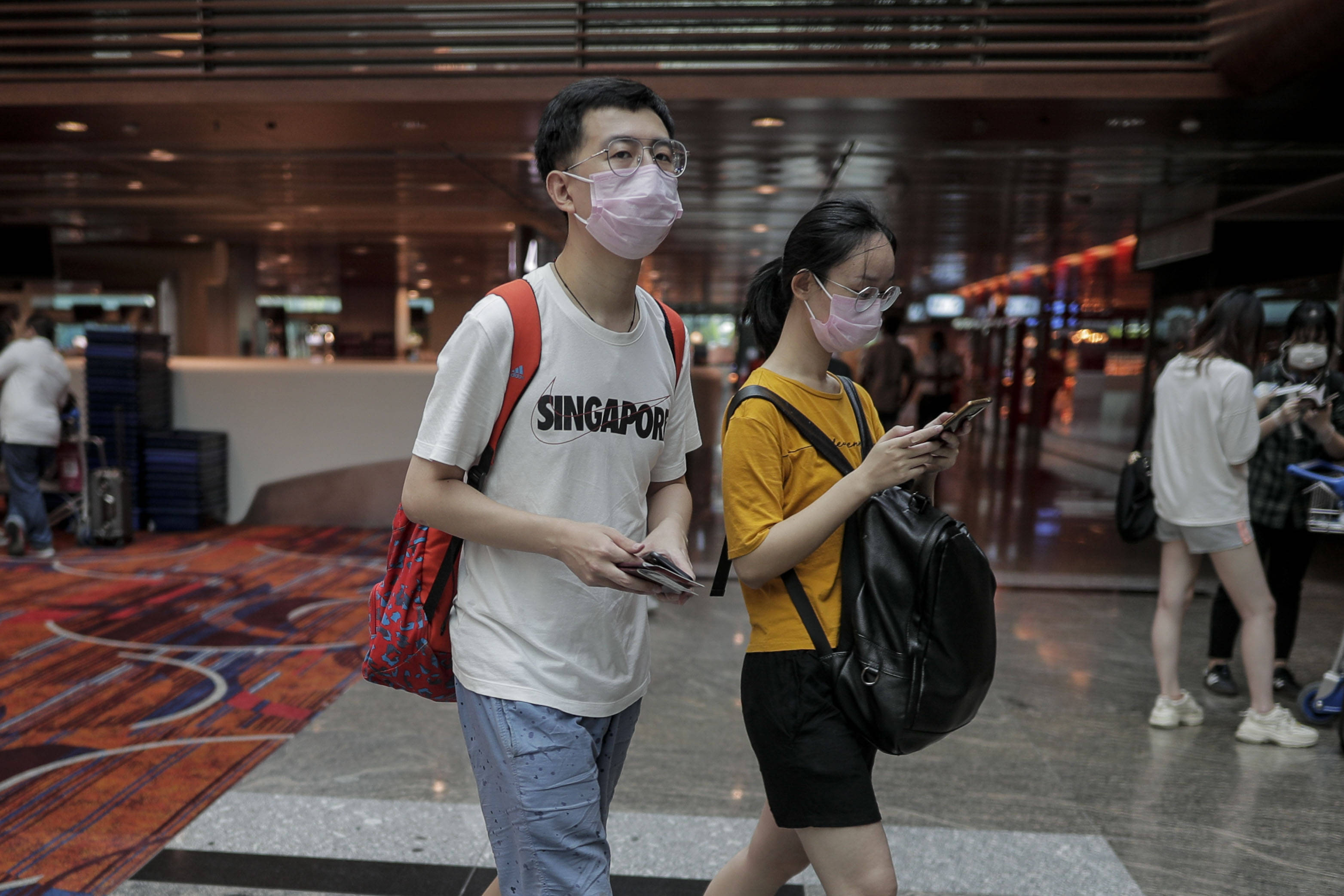 6月9日,戴口罩的乘客抵达新加坡樟宜机场候机厅.