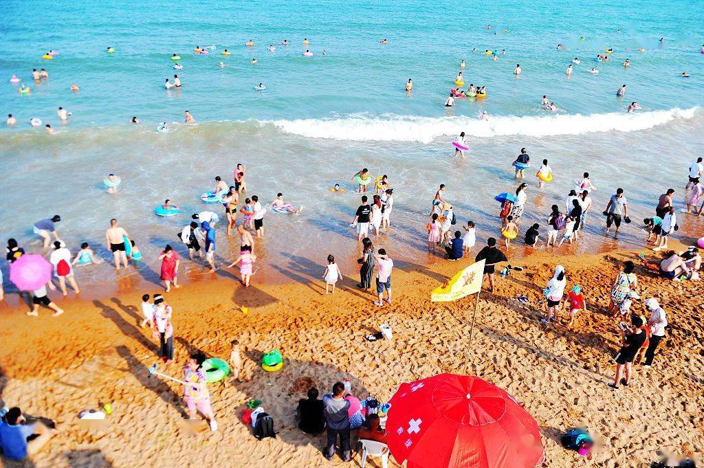 2020年7月20日,山东青岛西海岸新区金沙滩海水浴场,游客在沙滩和海水