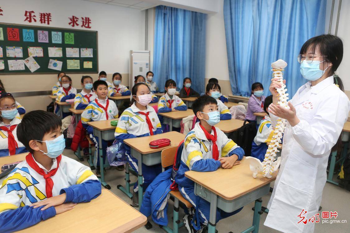 2020年12月9日,天津中医药大学的研究生在课堂上为小学生讲解颈部按摩