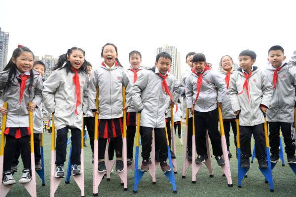 12月17日,重庆市九龙坡区谢家湾小学学生在操场上练习踩高跷.