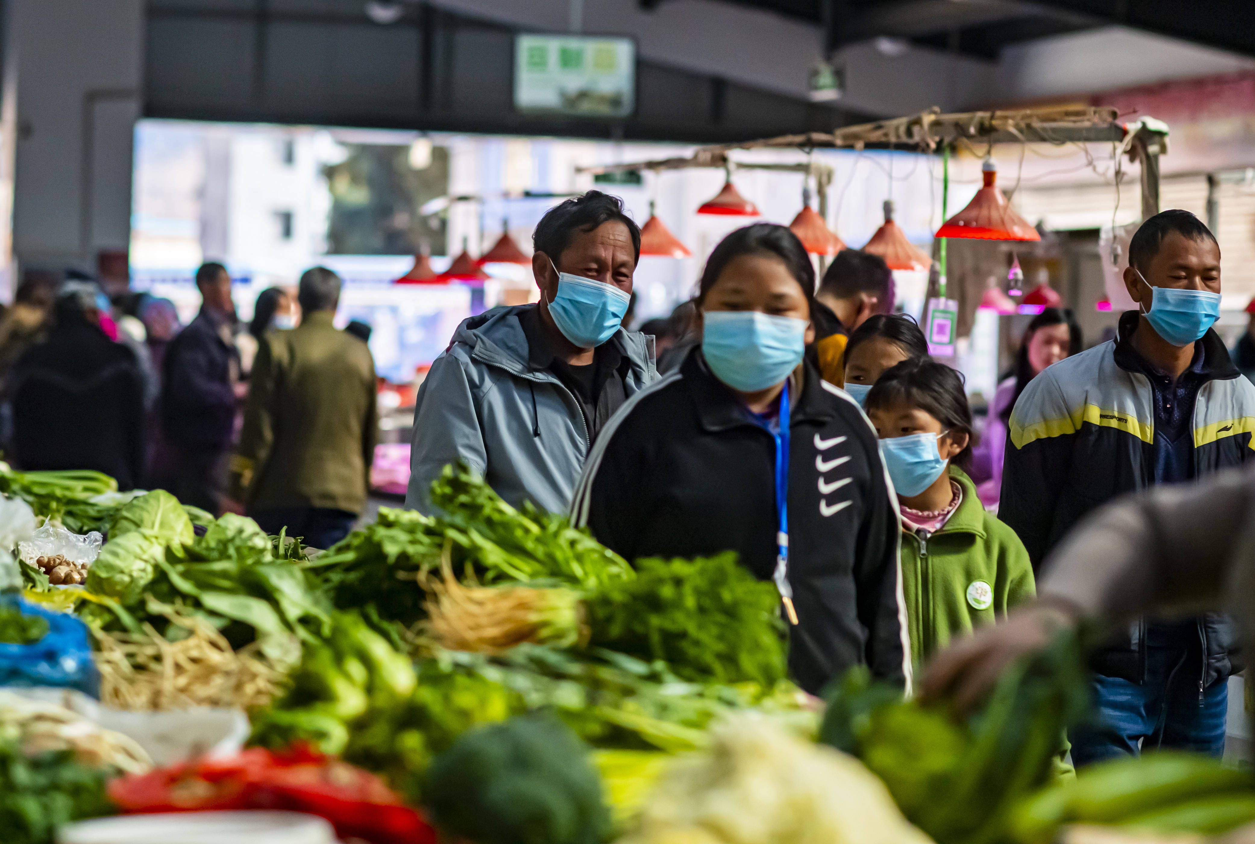 石元顺(左一)带着孩子们在农贸市场购买蔬菜(2月10日摄).
