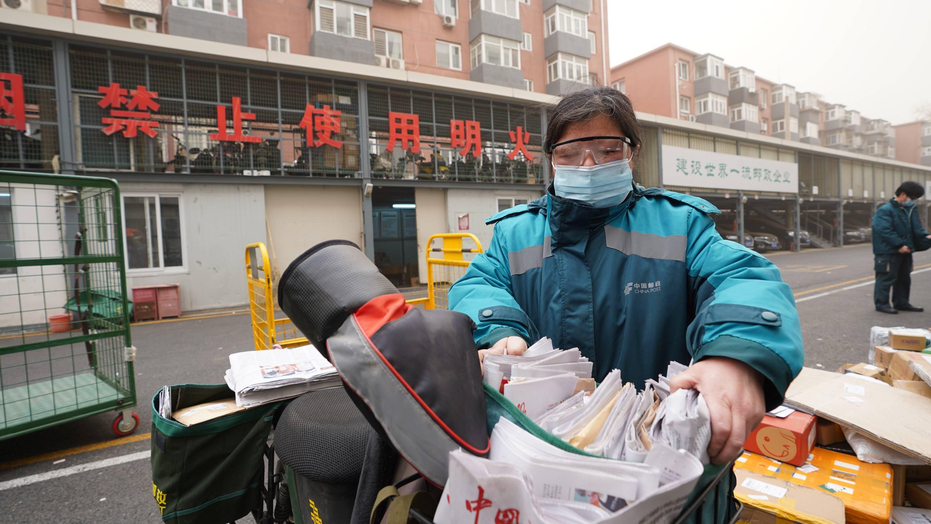 沙尘中邮政投递员全副武装出班投递