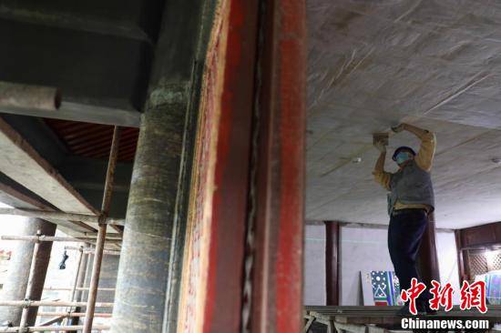 工作人员对飞龙阁内檐顶棚裱糊进行复原修复工作.