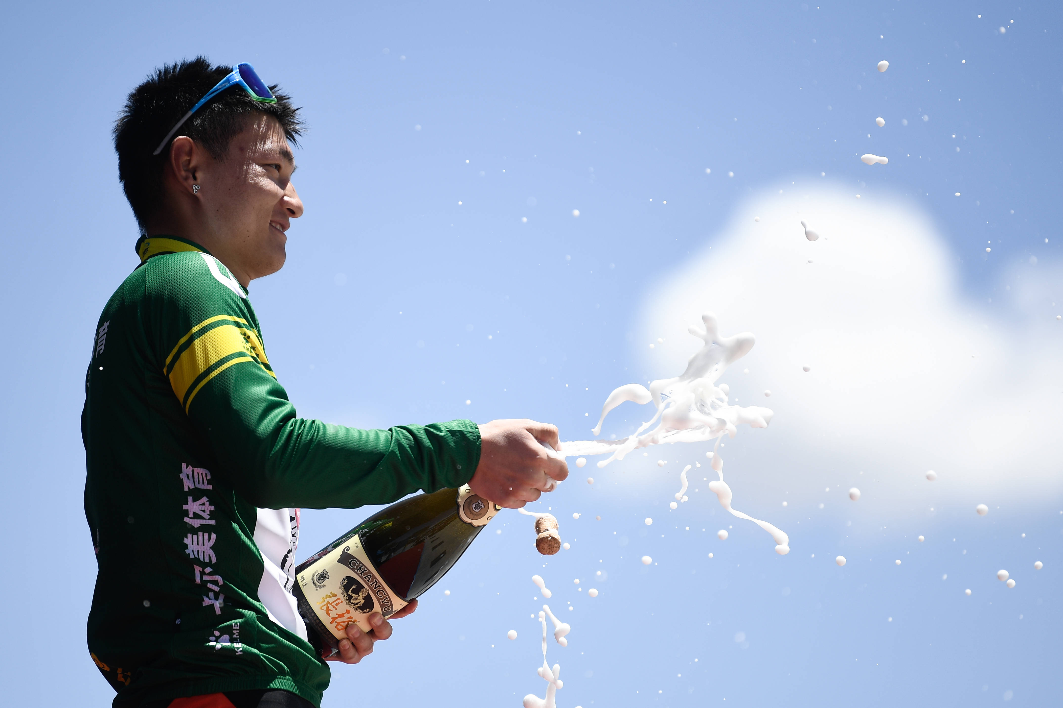 队选手李自森身着代表冲刺总积分第一名的绿衫在领奖台上喷洒香槟庆祝