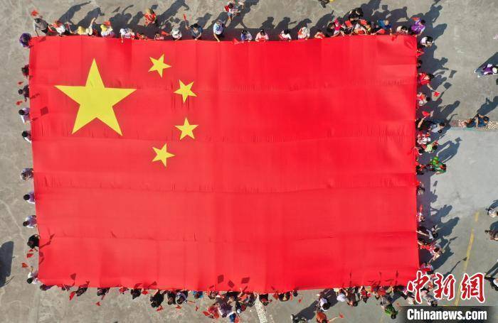 资料图:众多游客共同举起巨型国旗.