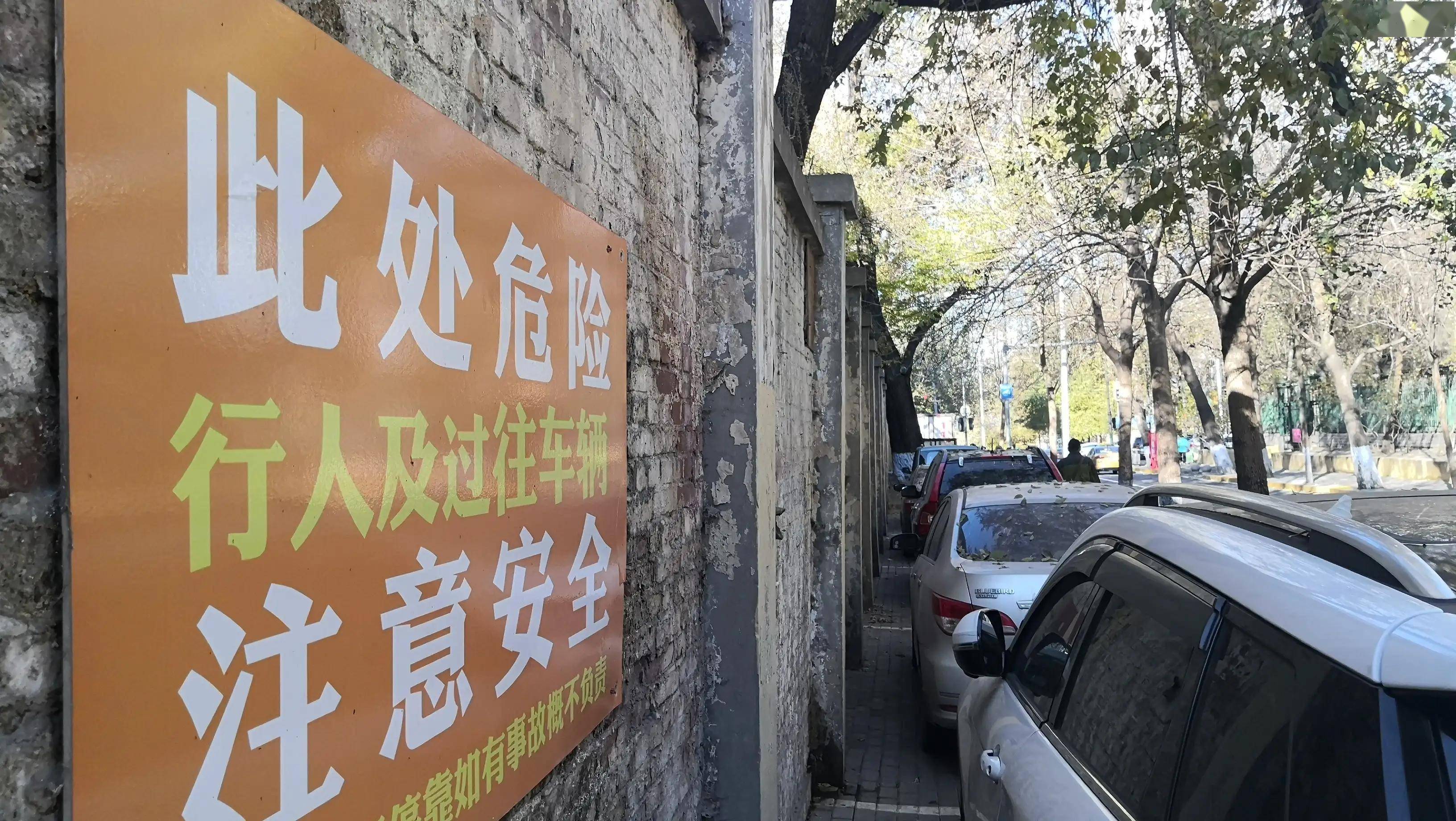 危墙上挂着多个警示牌还有人将车停在下面墙倒砸车算谁的责任