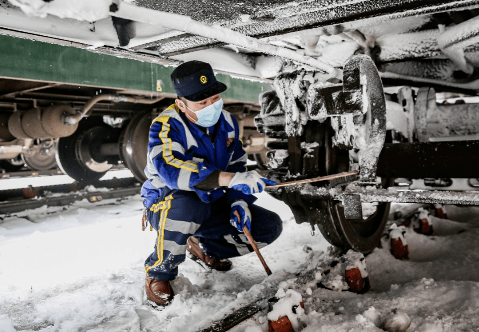 三棵树车辆段持续的大风雪使动车组底部和转向架挂满积雪积冰.