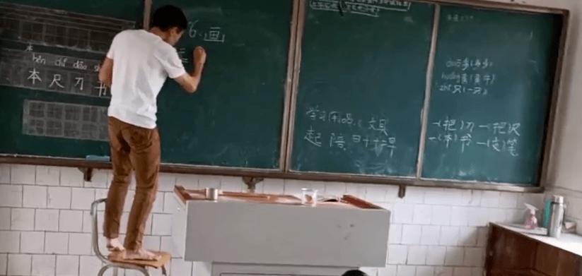 1.65米乡村教师赤脚站凳子上写板书