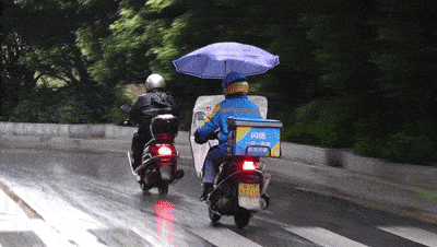 不仅自己身穿雨衣,给爱车也加把伞,在风中硬撑的伞看起来比小哥还辛苦