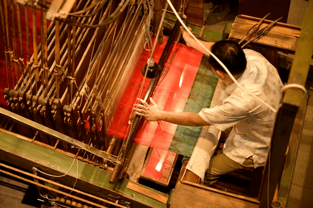 图据锦点嗡嗡的织机旁穿着华美唐装的匠人在现场展示蜀锦的织造技艺