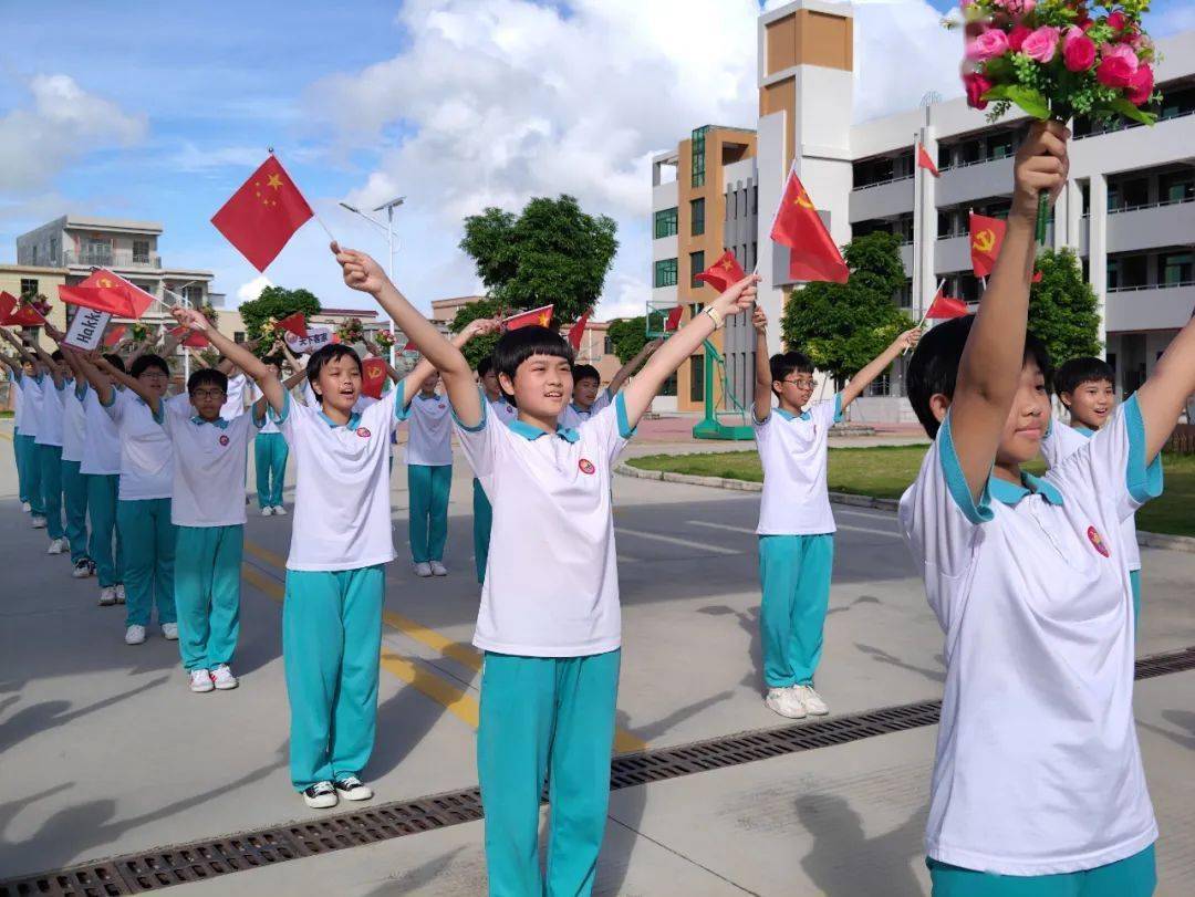 在赤溪中学大门前,师生们挥舞着手中的旗帜,鲜花和标语牌,跟随音乐的