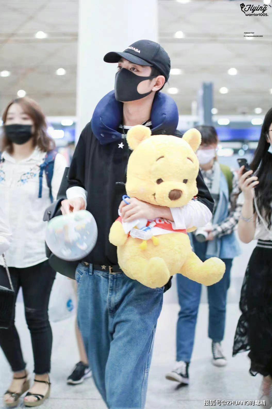 肖战身穿黑色t恤下带牛仔阔腿裤,手抱着小布熊低调出现在机场