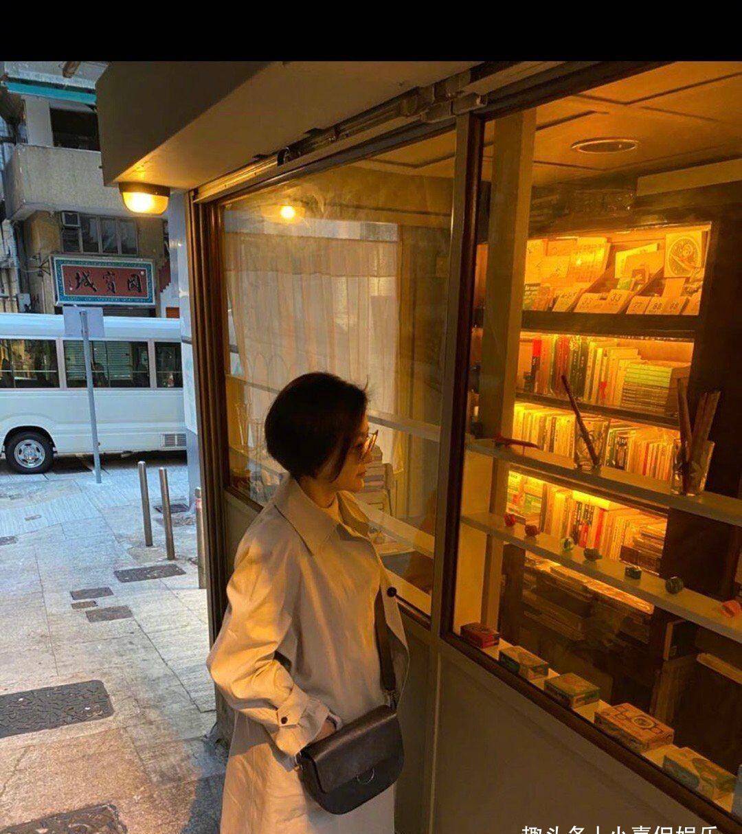 林青霞穿着一件棕色风衣,站在书店看书的她的背影很温馨,之前短发的她