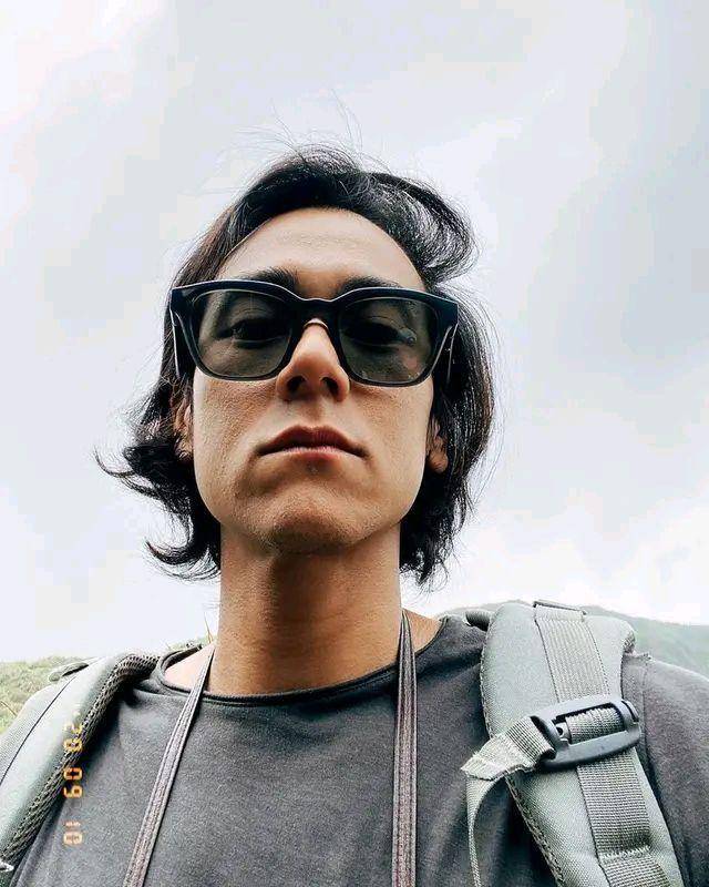 照片中彭于晏身穿一套休闲的登山装,带着墨镜,头发看上去显得又长又